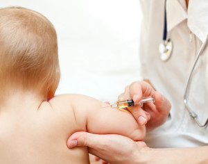 Doctor giving a child an intramuscular injection in arm, shallow DOF